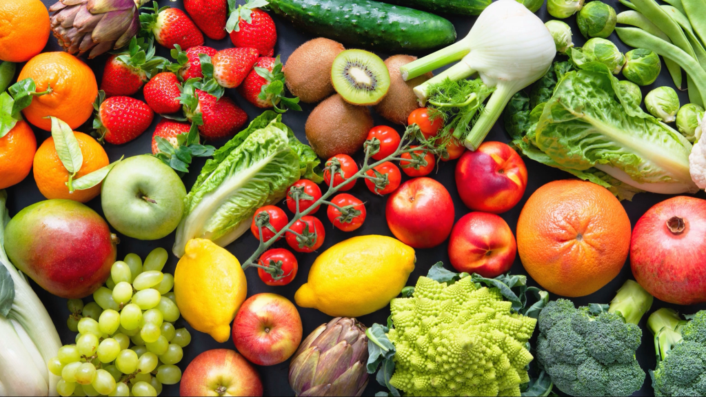 Strawberries, lemons, apples, tomatoes, broccoli, and other fruits and veggies on a table