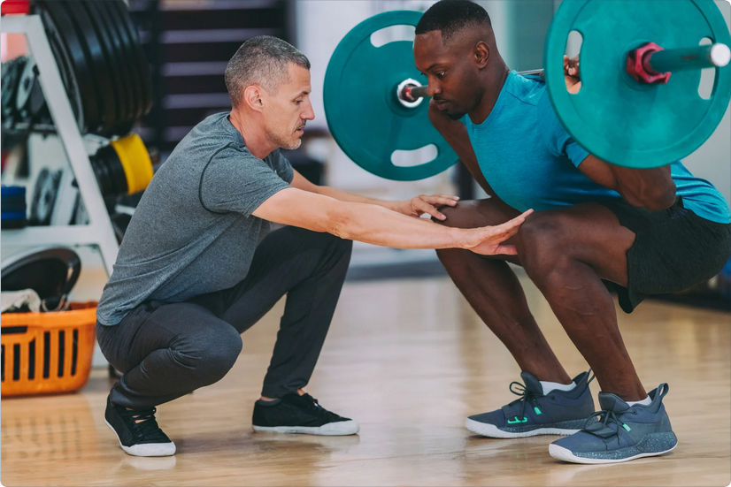 Personal trainer helping an athlete with squat form